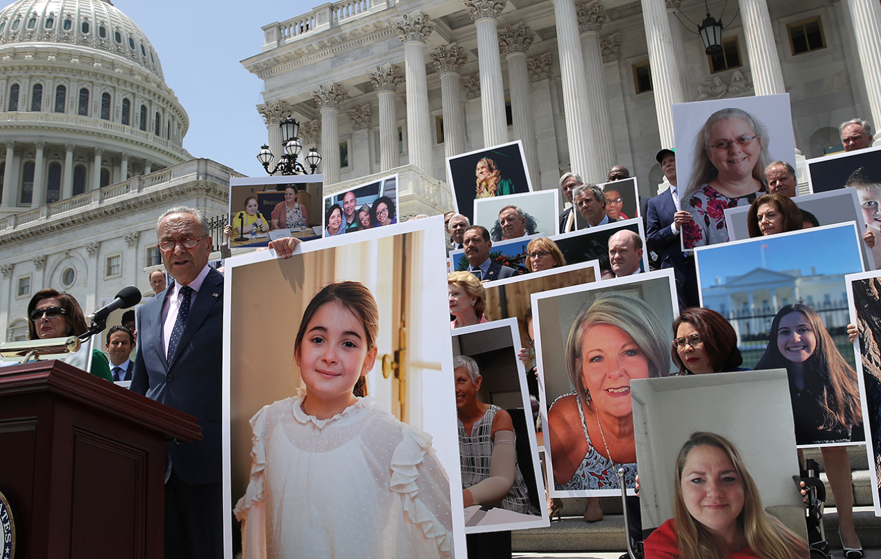 Large pictures of people held up during a speech on government building steps