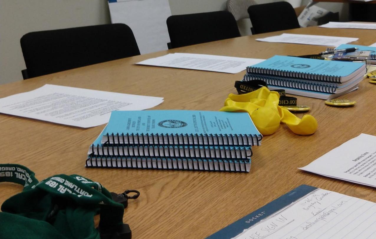 a meeting table with blue DCTU contracts, paper and pens