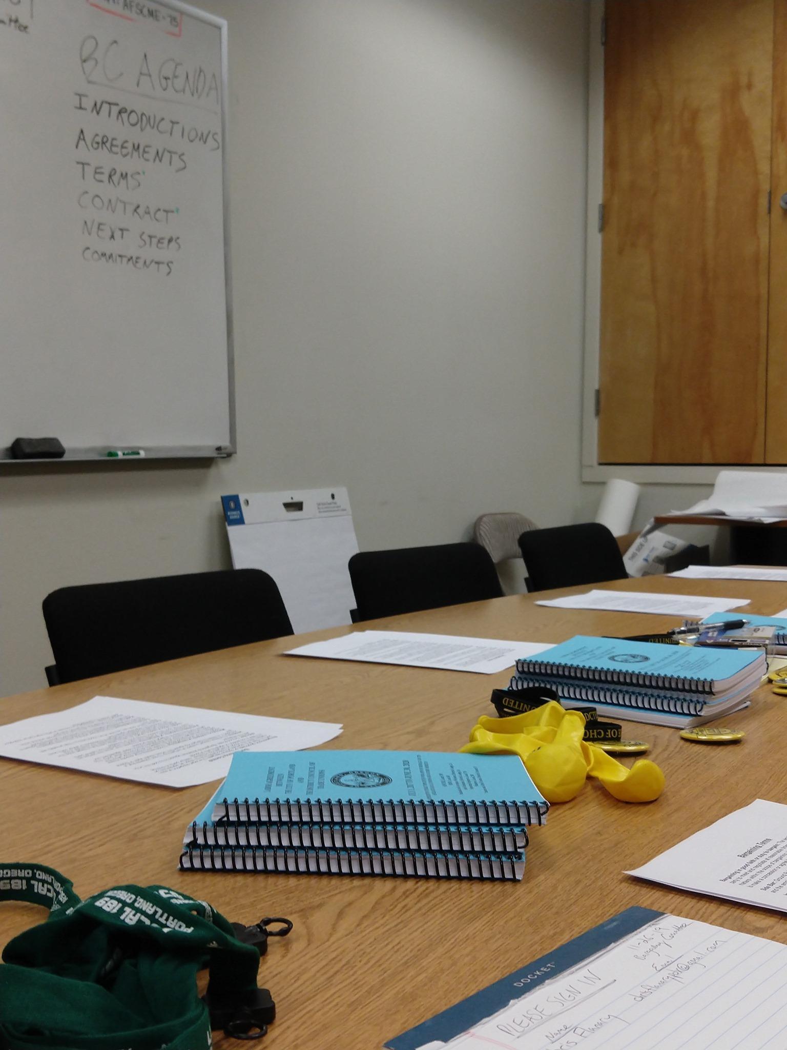 a meeting table with blue DCTU contracts, paper and pens